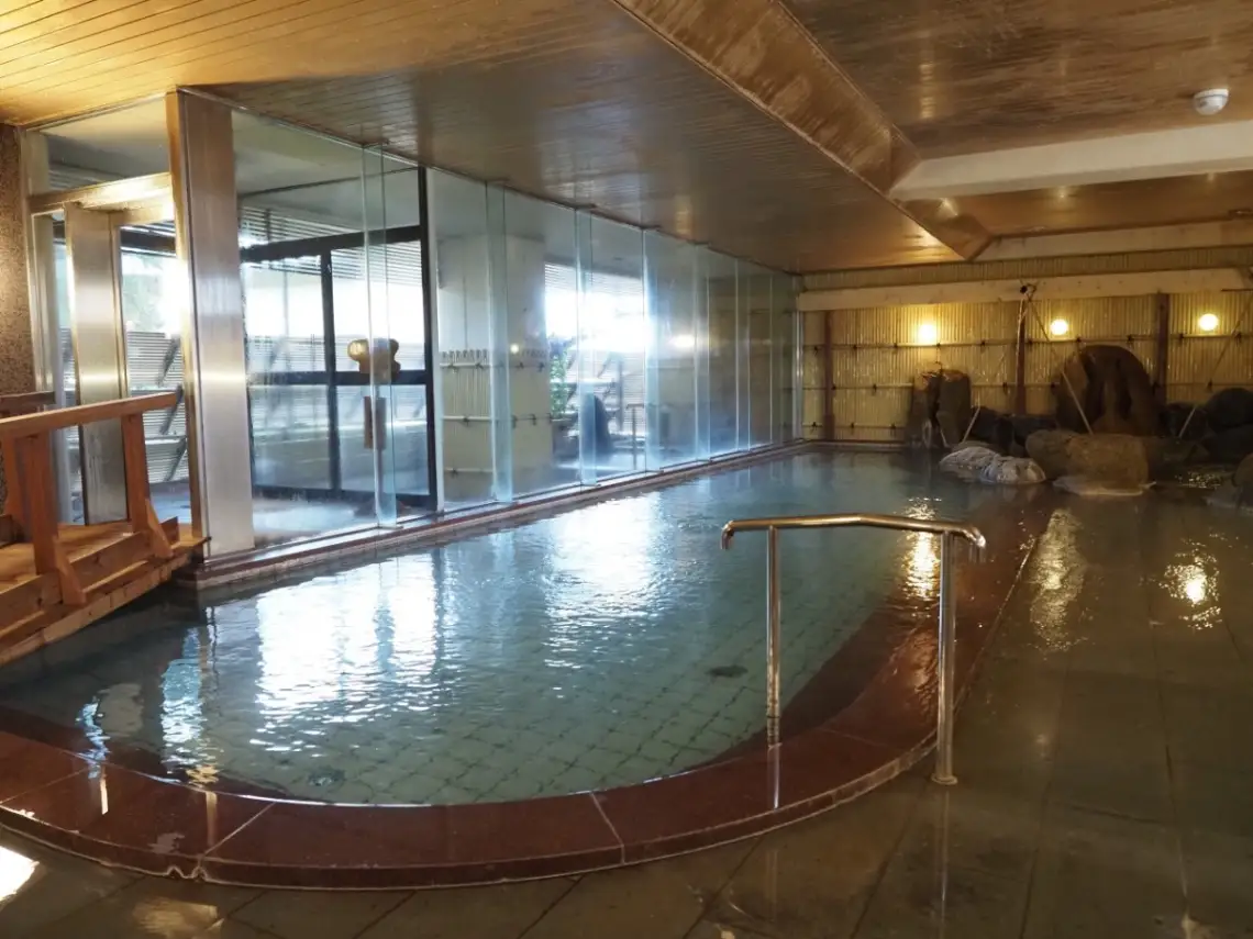 「あわづ温泉 喜多八」の女湯の内風呂。とても広く、奥には打たせ湯があり、手前には露天風呂へわたる橋がある